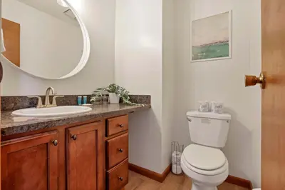 a bathroom with a toilet and a sink and a mirror at Modern Retreat with Forest Views 3BR Near Airport & Downtown in Gahanna