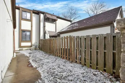a wooden fence in front of a house with snow at Modern Retreat with Forest Views 3BR Near Airport & Downtown in Gahanna
