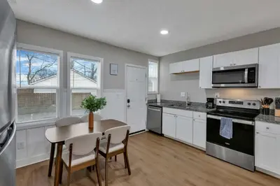 a kitchen with white cabinets and a table with chairs at Perfect Short Stay in Historic Columbus Walkable Modern & Easy in Columbus