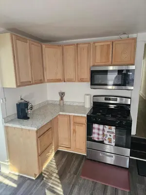 a kitchen with wooden cabinets and a stove top oven at Furnished 2-bedroom Downtown Anderson IN in Anderson