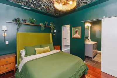 a green bedroom with a bed and a bathroom at Velvet Haus Downtown 3rd Floor Deck Backyard in Cincinnati