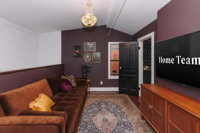 a living room with a brown couch and a flat screen tv at Velvet Haus Downtown 3rd Floor Deck Backyard in Cincinnati