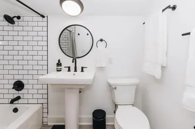 a white bathroom with a sink and a mirror at Velvet Haus Downtown 3rd Floor Deck Backyard in Cincinnati