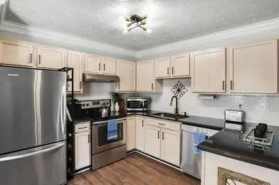 a kitchen with white cabinets and a stainless steel refrigerator at Spacious King Suite, Horses, Fire Pit, Garage in Lexington