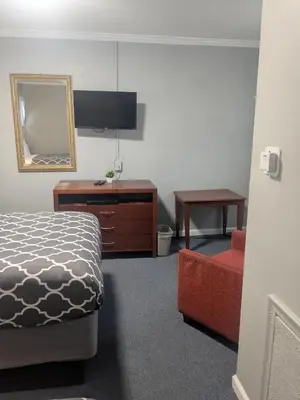 a bedroom with a bed and a dresser and a mirror at Southland Motor Lodge Hotel in Woodhaven