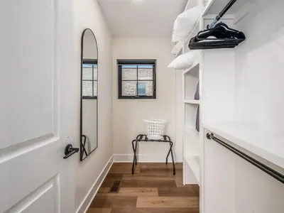 a hallway with white walls and a mirror and a chair at Rooftop Patio, Hot Tub and Games City Escape in Columbus