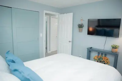 a bedroom with a white bed and a flat screen tv at Huber Heights Home w/Hot Tub near Rose Music/WPAFB in Dayton