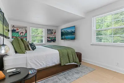 a bedroom with a bed and a table and two windows at Blissful Serenity - Walk to Lake Milton with Hot Tub in Lake Milton