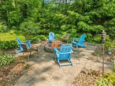 a patio with blue chairs and a fire pit at Blissful Serenity - Walk to Lake Milton with Hot Tub in Lake Milton