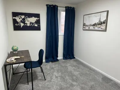 a room with a table and a chair and blue curtains at Charming Mentor Home w/ Fenced Backyard in Mentor