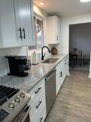 a kitchen with white cabinets and a sink and a stove at Charming Mentor Home w/ Fenced Backyard in Mentor