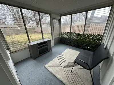 a screened in porch with a chair and a television at Charming Mentor Home w/ Fenced Backyard in Mentor