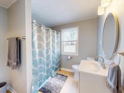 a bathroom with a sink and a toilet and a mirror at Stylish Home Near Historic Downtown & Lake Erie in Willoughby