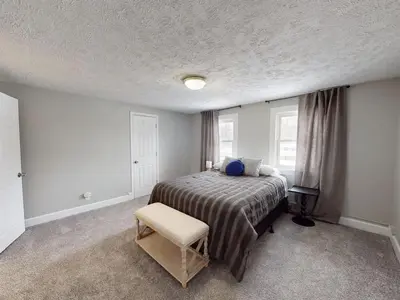 a bedroom with a bed and a chair in it at Stylish Home Near Historic Downtown & Lake Erie in Willoughby