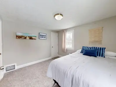 a bedroom with a large white bed with a blue pillow at Stylish Home Near Historic Downtown & Lake Erie in Willoughby