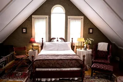 a bedroom with a bed and two chairs in a attic at Clifford House Private Home B&B in Cleveland