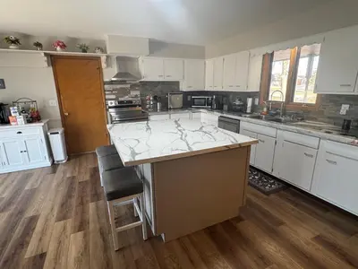 a large kitchen with white cabinets and a large island at Muncie 3 bedroom 2 bath brick home in Muncie
