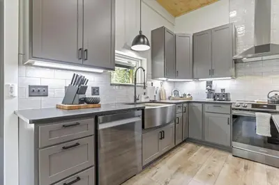 a kitchen with stainless steel appliances and wooden floors at Pine Grove Barndominium in Sugar Grove