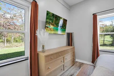 a bedroom with a dresser and two windows at Pine Grove Barndominium in Sugar Grove
