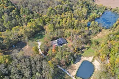 an aerial view of a house on a hill next to a lake at Pine Grove Barndominium in Sugar Grove