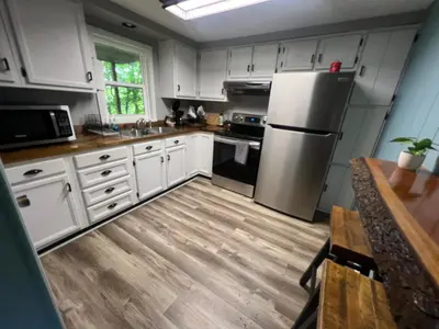 a kitchen with white cabinets and a stainless steel refrigerator at Salt Creek Cabin in Chillicothe