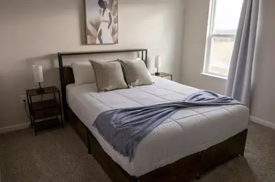a bedroom with a bed with white sheets and a window at Holistic Campus Rental, LLC in Oxford