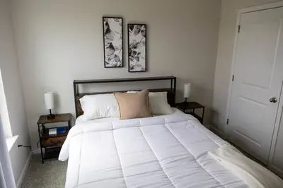 a white bed in a bedroom with two pictures on the wall at Holistic Campus Rental, LLC in Oxford