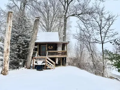 a log cabin in the snow in the woods at Walnut Creek Cabin in Chillicothe