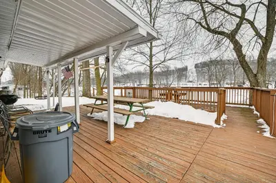 a wooden deck with a picnic table and a trash can at Deck and Fire Pit! Muskingum Fishing Cabin in Dresden
