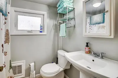 a bathroom with a toilet and a sink and a window at Deck and Fire Pit! Muskingum Fishing Cabin in Dresden