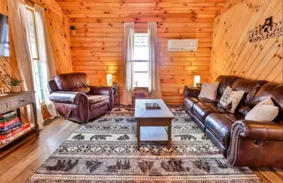 a living room with leather couches and a table at Timber Ridge Cabin in Louisa