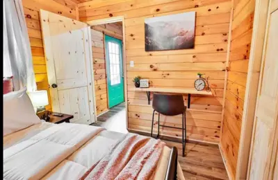 a bedroom with a bed and a desk in a wooden wall at Timber Ridge Cabin in Louisa