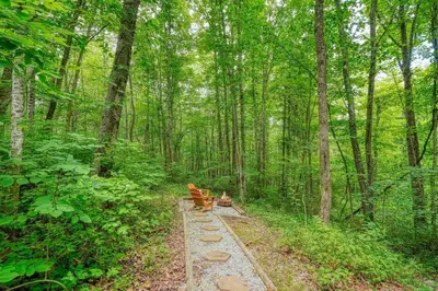 two benches sitting on a path in the woods at Romantic Logan Cabin with Private Year Round Hot Tub Near Hocking Hills in Logan