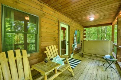 a porch of a cabin with two chairs and a television at Romantic Logan Cabin with Private Year Round Hot Tub Near Hocking Hills in Logan