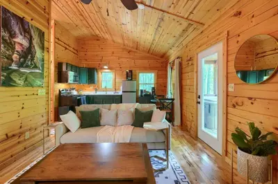 a living room in a log cabin with a couch at Romantic Logan Cabin with Private Year Round Hot Tub Near Hocking Hills in Logan