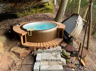 a jacuzzi tub with a wooden deck and a bath tub at Hillside Haven Treehouse Cabin in Rockbridge