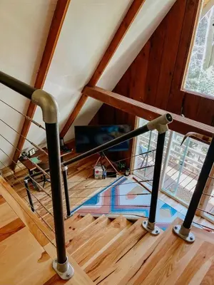a staircase in a attic with a metal railing at Hillside Haven Treehouse Cabin in Rockbridge