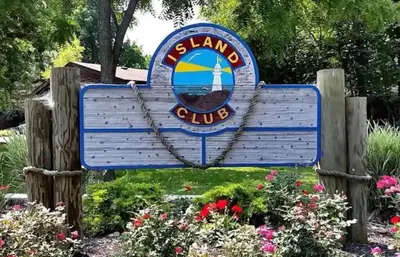 a blue sign for a marina club with flowers at Put-in-Bay Island Club #63 in Put-in-Bay
