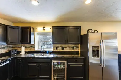 a kitchen with black cabinets and a white refrigerator at Shop, Dine and Play Cincinnati Retreat! in Cincinnati