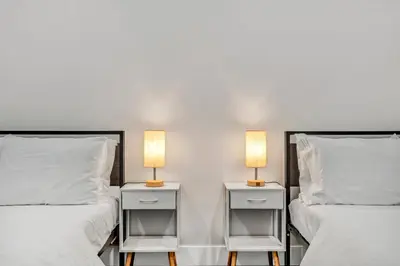 two beds with white sheets and lamps on them at The Pearl Hideaway Cozy West Side Gem Near DT in Cleveland