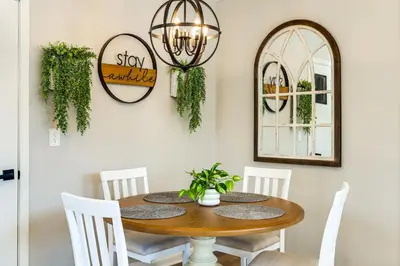 a dining room table with white chairs and a mirror at Stay in the Heart of London! Walkable, Modern Home in London