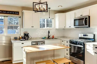 a kitchen with white cabinets and a stove top oven at Stay in the Heart of London! Walkable, Modern Home in London