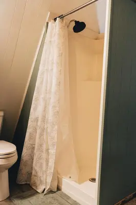 a shower with a white shower curtain in a bathroom at The Rustic Triangle A-Frame in Perrysville