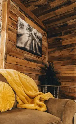 a living room with a couch and a tv on a wall at The Rustic Triangle A-Frame in Perrysville