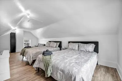 two beds in a bedroom with white walls and wood floors at Modern Stylish Urban Haven 4 Bedroom 2 Bath - Dog Friendly in Akron