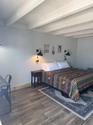 a bedroom with a bed with a table and lamps at Tecumseh Inn & Suites in Tecumseh