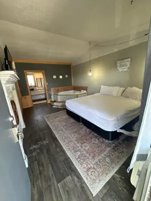 a bedroom with a large bed and a rug at Tecumseh Inn & Suites in Tecumseh