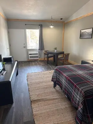 a room with a bed and a dining room with a table at Tecumseh Inn & Suites in Tecumseh