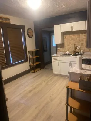 a kitchen with white cabinets and a wooden floor at Rooms for Rent in Cleveland