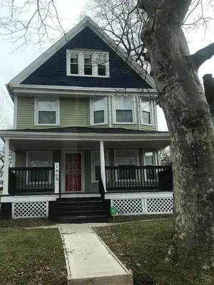 a green house with a red door and a tree at Rooms for Rent in Cleveland